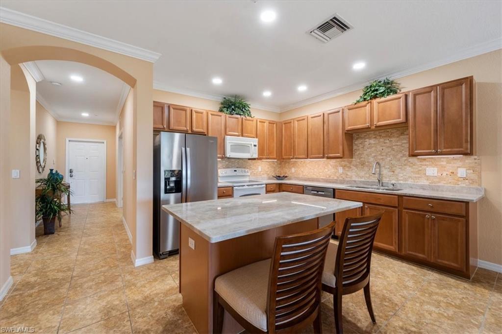 14981 Reflection Key Circle, Unit 322 Fort Myers, FL 33907 - Photo 5 of 35 a kitchen with a table chairs refrigerator and microwave