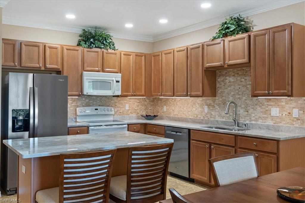 14981 Reflection Key Circle, Unit 322 Fort Myers, FL 33907 - Photo 6 of 35 a kitchen with kitchen island granite countertop a sink stove and refrigerator