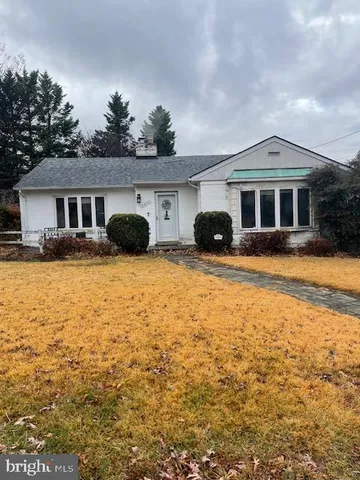 a front view of house with yard and trees in the background