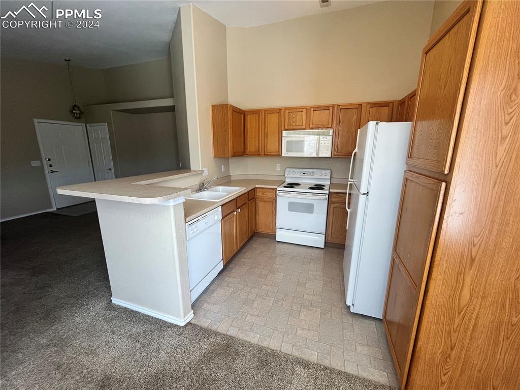 3731 Riviera Grove, Unit 203 Colorado Springs, CO 80922 - Photo 8 of 22 a kitchen with stainless steel appliances a refrigerator a sink a stove and white cabinets