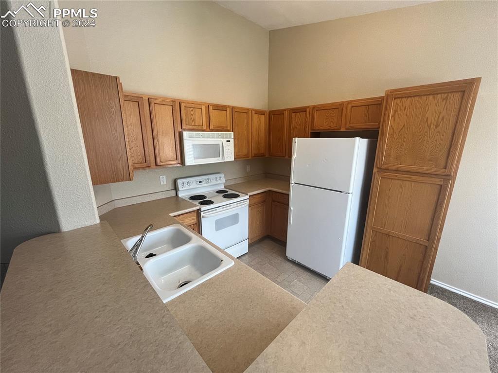 3731 Riviera Grove, Unit 203 Colorado Springs, CO 80922 - Photo 9 of 22 a kitchen with stainless steel appliances a refrigerator a sink a stove a microwave a sink