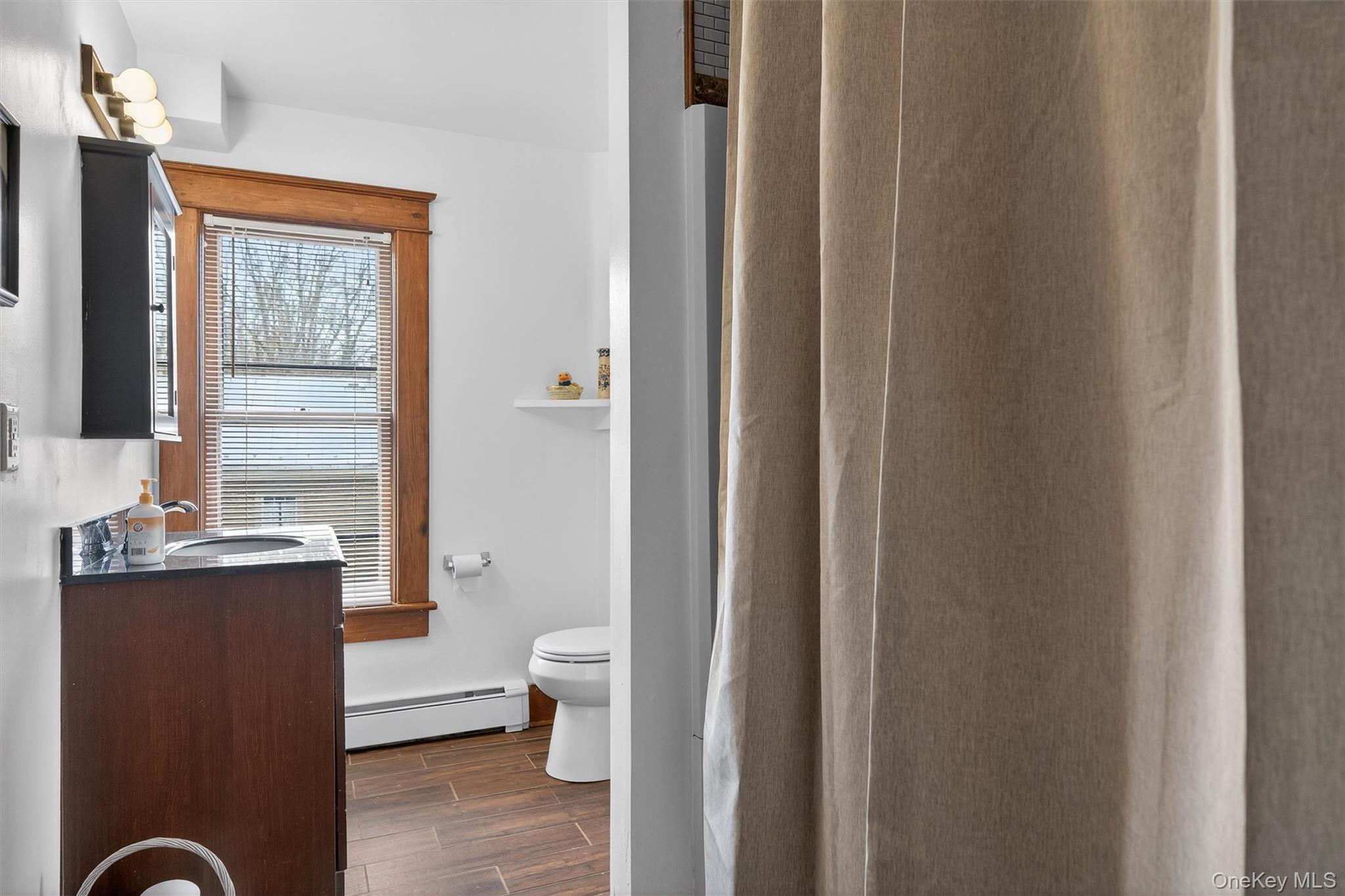 48 Kirks Road Narrowsburg, NY 12764 - Photo 34 of 50 Full bath featuring vanity, a shower with shower curtain, wood finish floors, and a baseboard heating unit