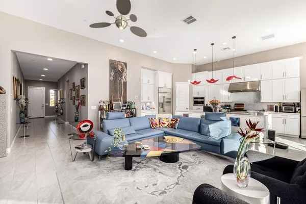 a living room with furniture kitchen view and a chandelier