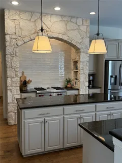 a kitchen with kitchen island granite countertop a sink a counter space cabinets and stainless steel appliances