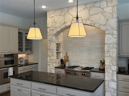 a kitchen with stainless steel appliances granite countertop a sink a stove and a wooden floors