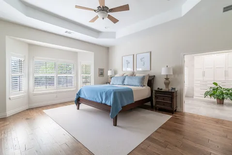 a bedroom with a large bed and a chandelier fan
