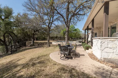 a view of a patio with table and chairs and potted plants and large trees