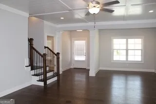 an empty room with wooden floor fan and windows