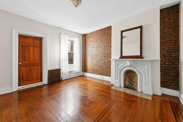 an empty room with fireplace wooden floor and windows