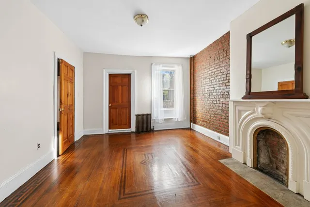 a view of a livingroom with wooden floor and a fireplace