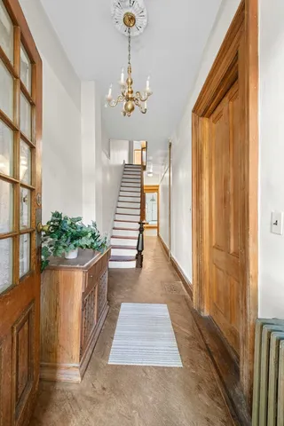 a view of a hallway with wooden floor and chandelier