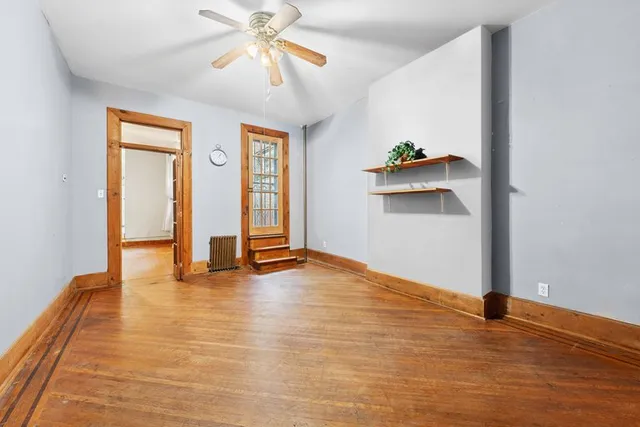 a view of an empty room with window and wooden floor