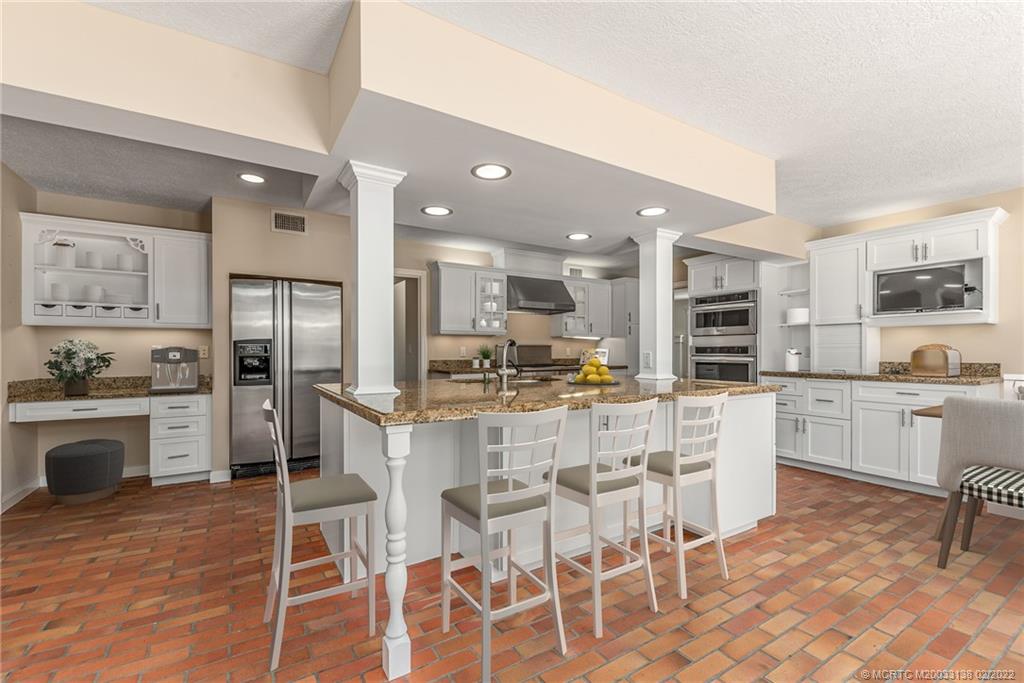 9 Middle Road Stuart, FL 34996 - Photo 13 of 32 a kitchen with stainless steel appliances granite countertop a stove top oven a sink a dining table and chairs