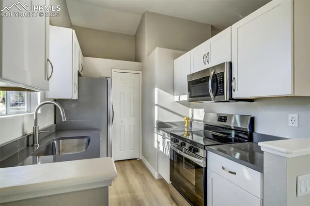 a kitchen with stainless steel appliances a sink a stove a microwave a refrigerator a sink and cabinets