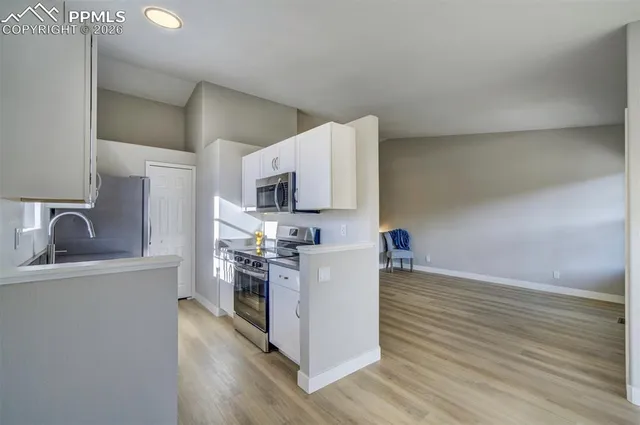 a kitchen with stainless steel appliances a microwave a stove and white cabinets with wooden floor