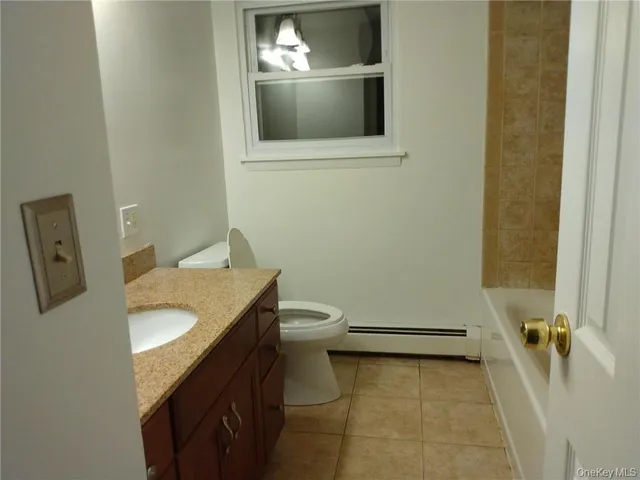 a bathroom with a granite countertop toilet sink and mirror