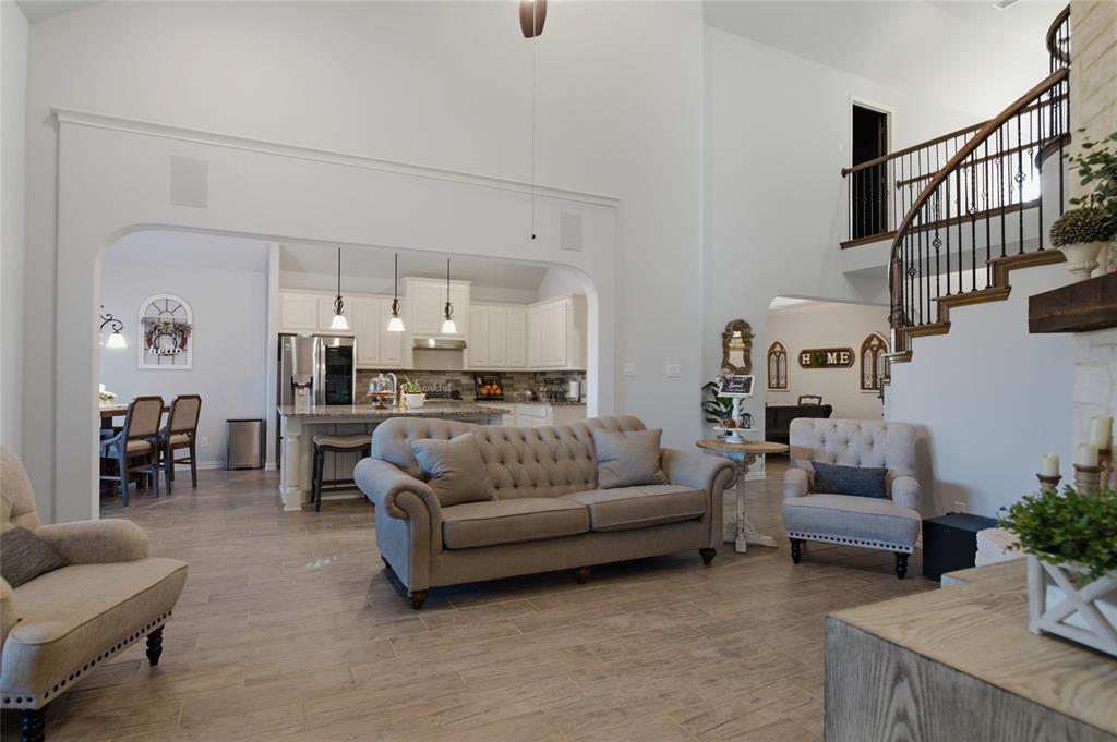 464 LeTara Ranch Drive Haslet, TX 76052 - Photo 9 of 37 Spacious living area featuring wood-finish flooring, a soaring two-story ceiling, and an elegant curved staircase with wrought iron balusters