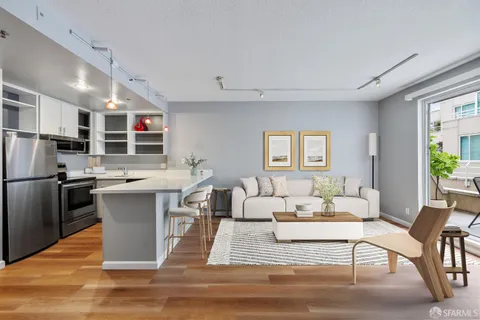 a living room with stainless steel appliances furniture and a kitchen view