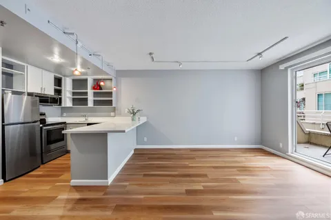 a kitchen with stainless steel appliances wooden floor and white cabinets
