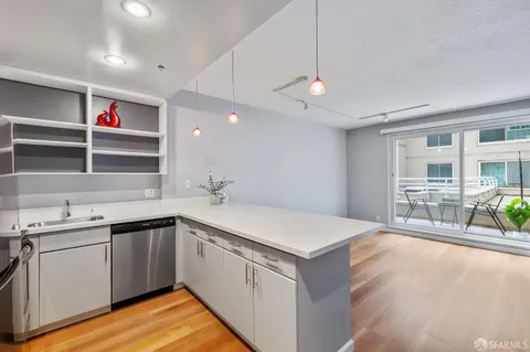 a kitchen with a sink and dishwasher with wooden floor