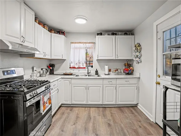 a kitchen with granite countertop white cabinets sink and stainless steel appliances