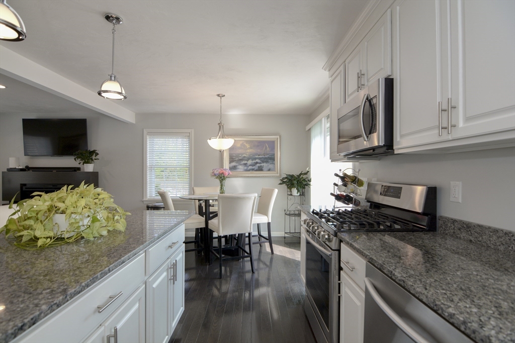 12 Gedney Drive Peabody, MA 01960 - Photo 9 of 41 a kitchen with stainless steel appliances granite countertop a stove top oven a sink a dining table and chairs with wooden floor