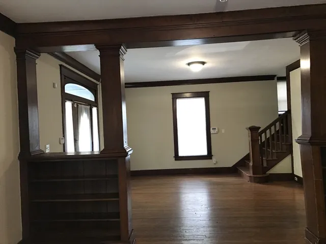 an empty room with wooden floor chandelier and windows