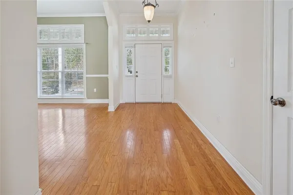 a view of an empty room with wooden floor and a window