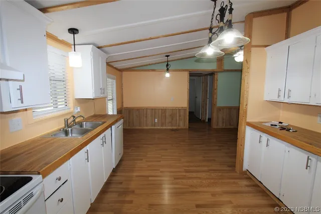 a view of a kitchen with kitchen island a sink stainless steel appliances cabinets and a counter top space