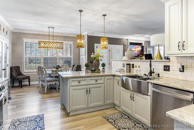 a kitchen with stainless steel appliances granite countertop a stove a sink dishwasher and white cabinets with wooden floor