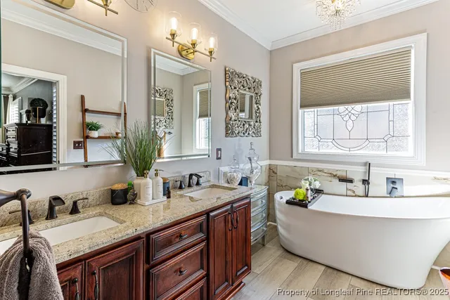 a bathroom with a granite countertop tub a double vanity sink a vanity a window and two mirror