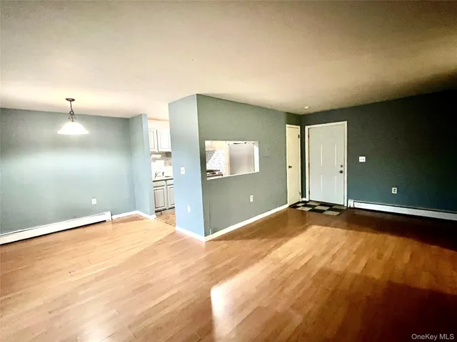 a view of an empty room with window and wooden floor