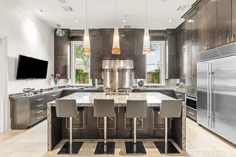 a kitchen with stainless steel appliances kitchen island granite countertop a sink and a refrigerator