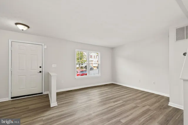 an empty room with wooden floor and window