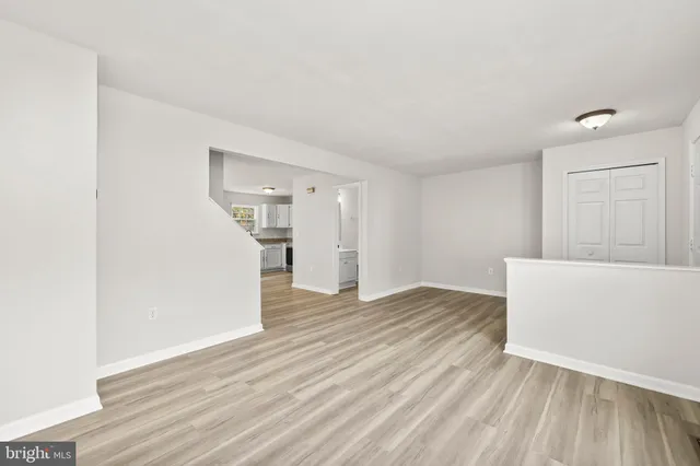 a view of empty room with wooden floor and kitchen