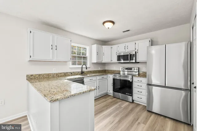 a kitchen with granite countertop a refrigerator stove top oven and sink
