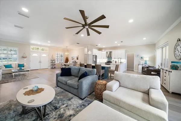 a living room with furniture a kitchen view and a chandelier