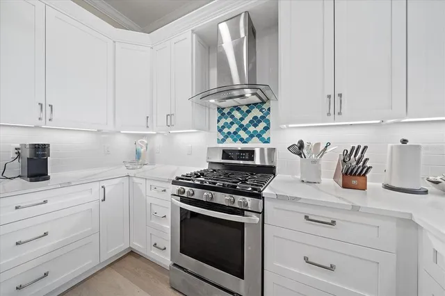 a kitchen with stainless steel appliances granite countertop white cabinets and a stove