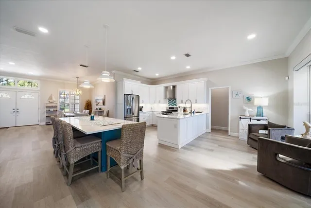 a large kitchen with kitchen island a sink a stove a dining table and chairs