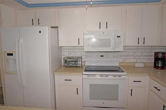 a kitchen with white cabinets and white appliances