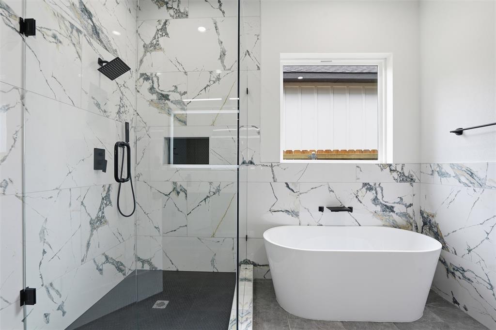 1111 Riverwood Road Dallas, TX 75217 - Photo 24 of 40 Contemporary bathroom featuring a freestanding soaking tub, a frameless glass shower enclosure with matte black fixtures, and floor-to-ceiling marbled tile