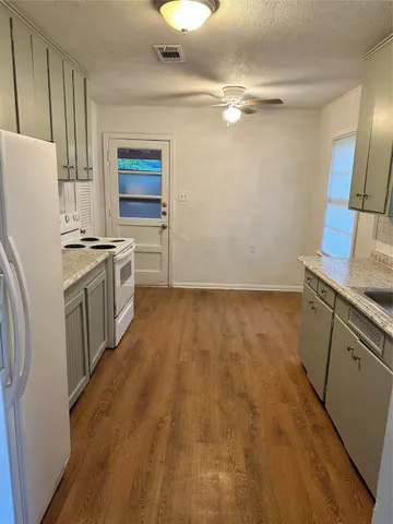 a kitchen with granite countertop a stove a sink and a refrigerator