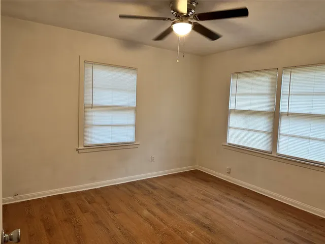 an empty room with a window and wooden floor