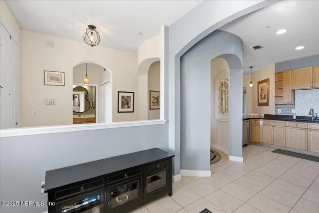 a living room with stainless steel appliances furniture a rug kitchen view and a table