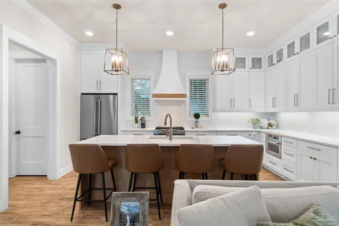 a kitchen with stainless steel appliances a dining table chairs and white cabinets