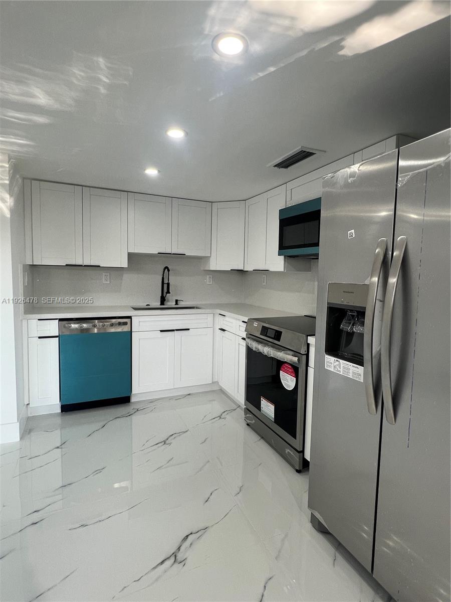 20610 Northeast 7th Court Miami, FL 33179 - Photo 11 of 38 a kitchen with a refrigerator a stove top oven a sink and dishwasher
