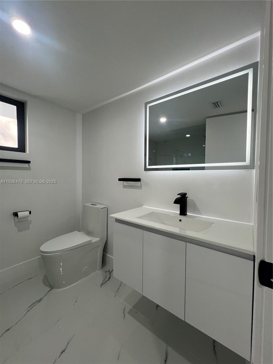 20610 Northeast 7th Court Miami, FL 33179 - Photo 20 of 38 a bathroom with a toilet a sink and mirror
