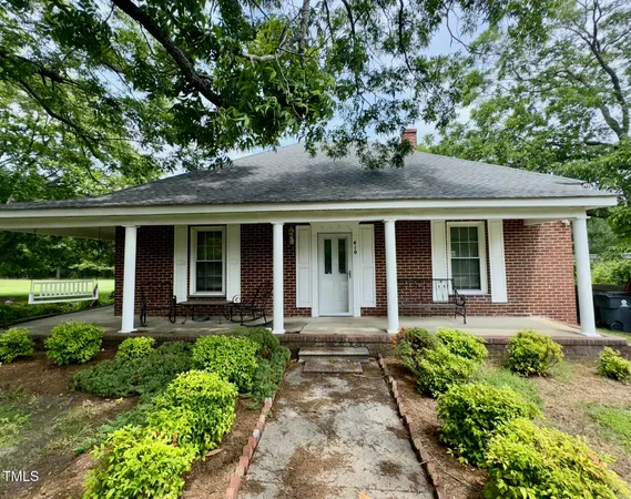 front view of a brick house with a yard table and chairs next to a yard