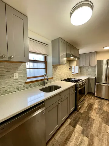 a kitchen with stainless steel appliances granite countertop a sink a stove and a refrigerator