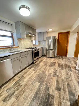 a large kitchen with granite countertop a sink stainless steel appliances and cabinets